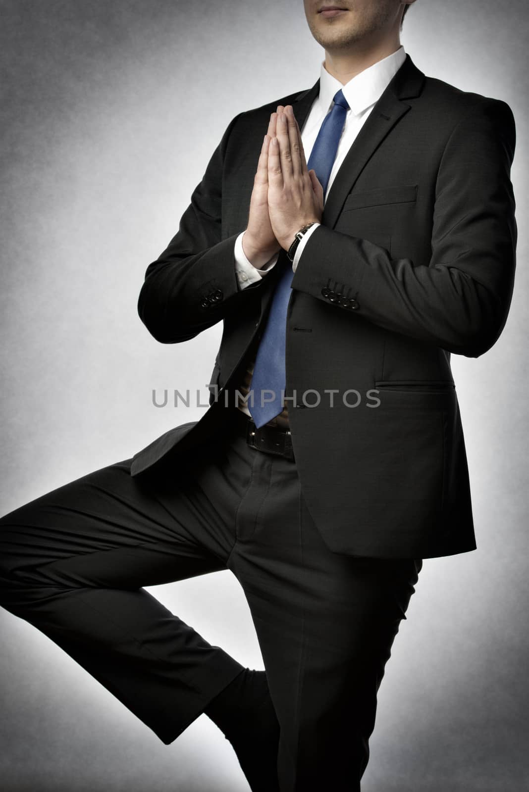 Businessman in dark suit is doing an yoga exercise