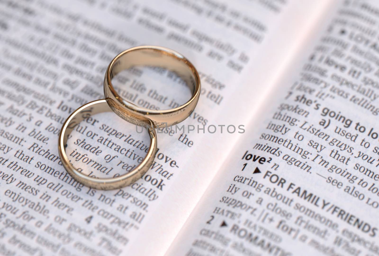 Couple of gold wedding rings on a dictionary page showing love definition  by Barbraford