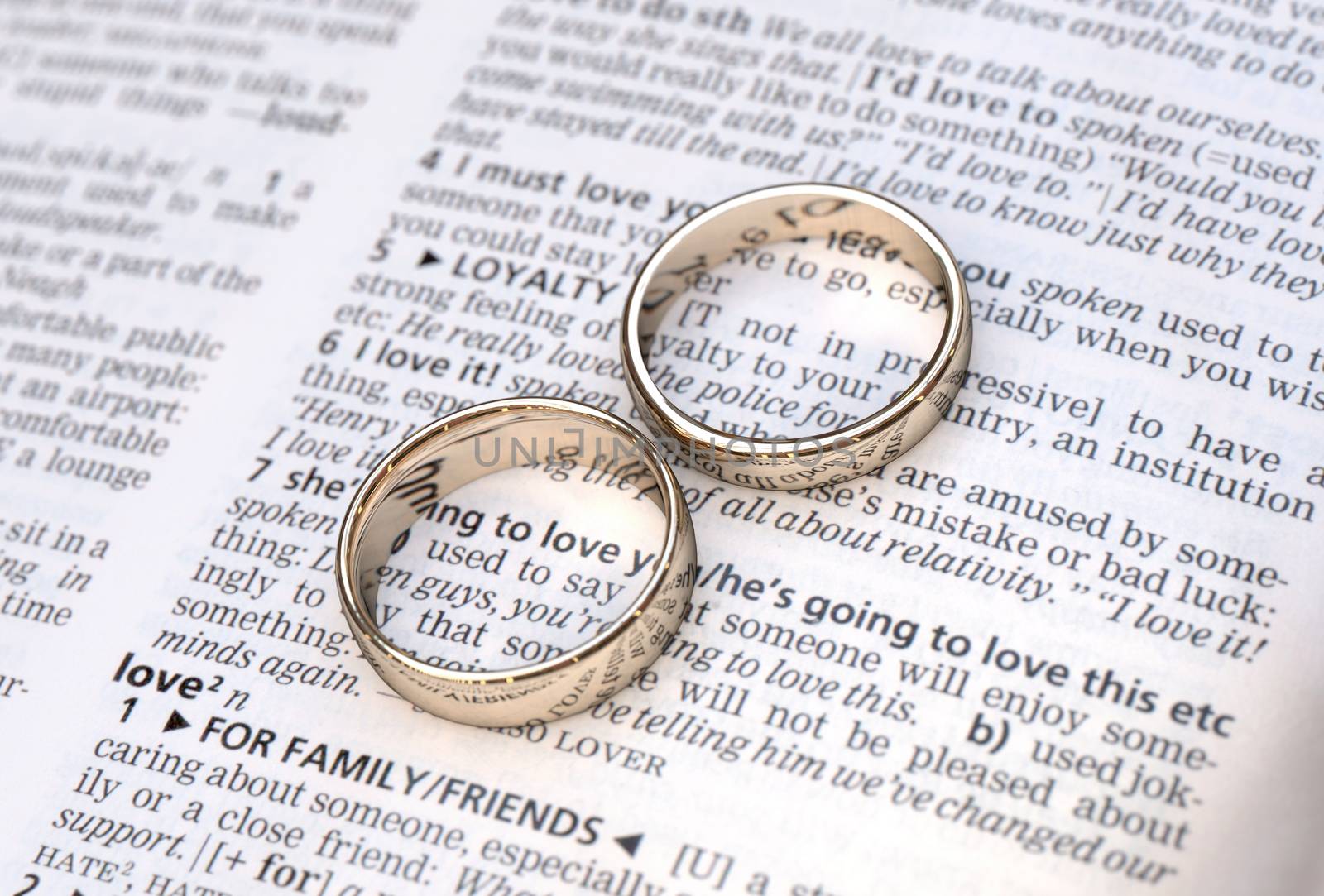 Wedding rings on a dictionary page showing love definition,  close up