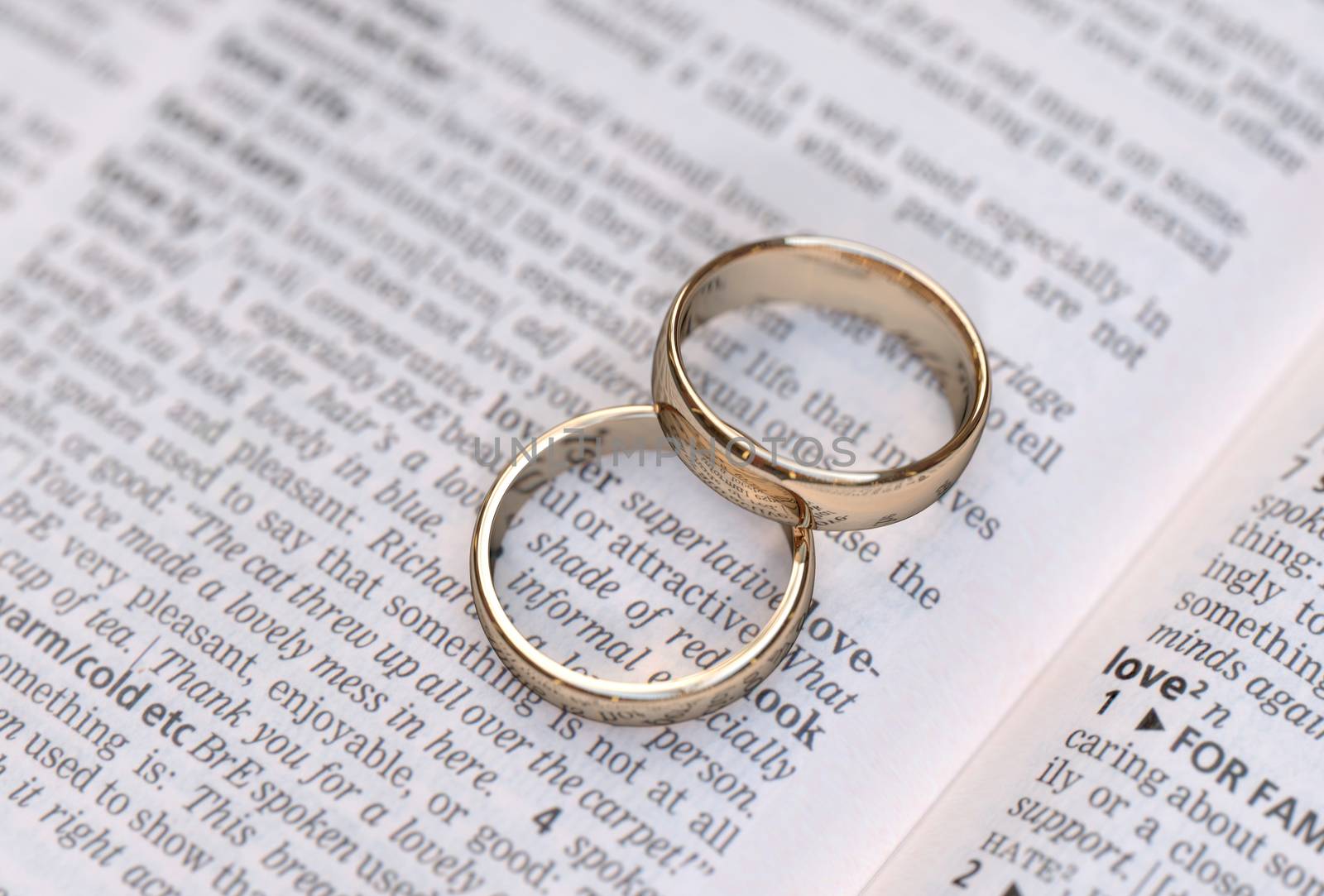 Wedding rings on a dictionary page showing love definition,  close up