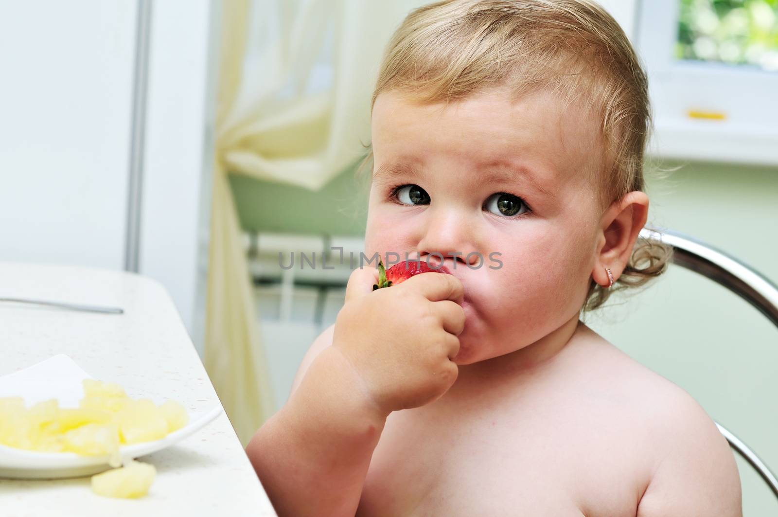 little funny baby girl eating fresh strawberry 