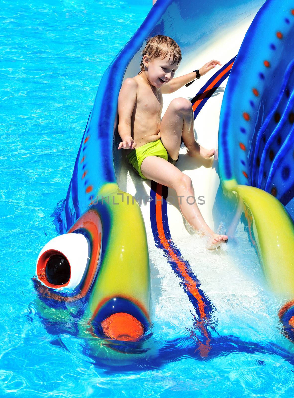  little boy sliding down a water slide  and having fun