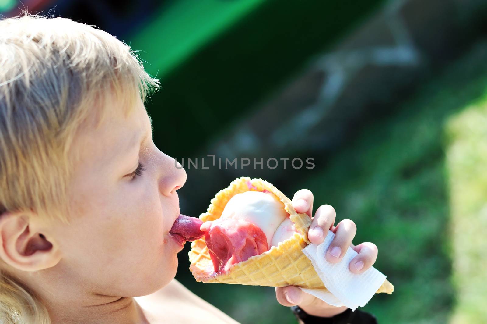 little boy licking ice cream in hot summer day