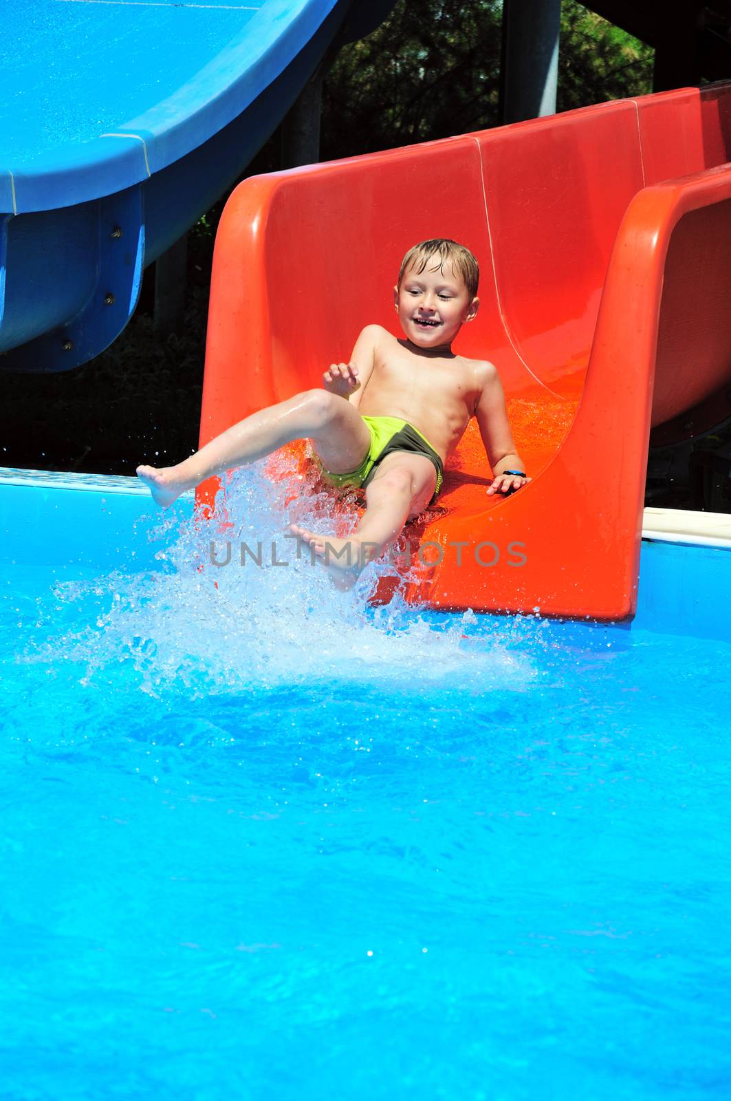 Cute little boy sliding down a water slide
