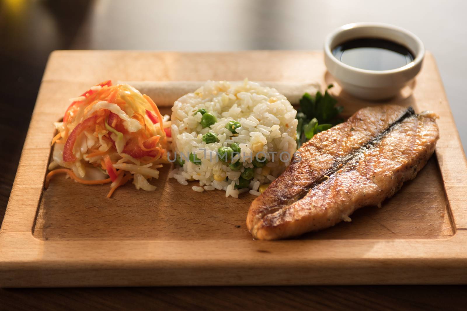 Grilled salmon with rice and vegetables at wooden table