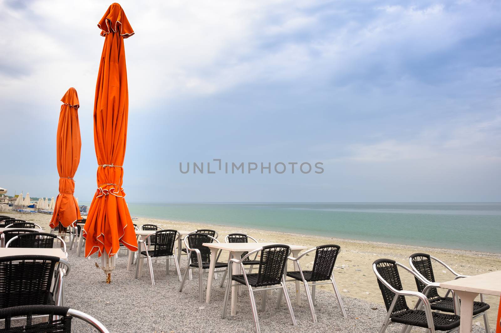 Beach cafe with empty tables and chairs placed at the sea waterfront