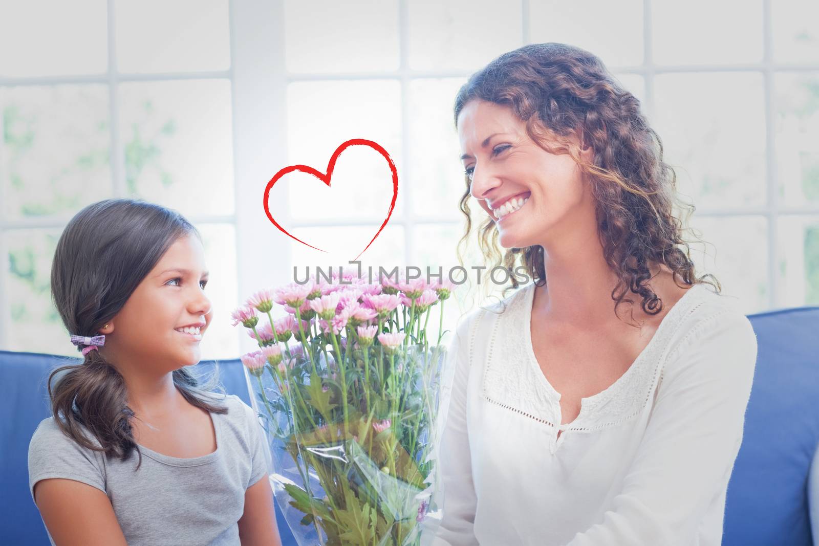 Heart against happy mother and daughter sitting on the couch with flowers