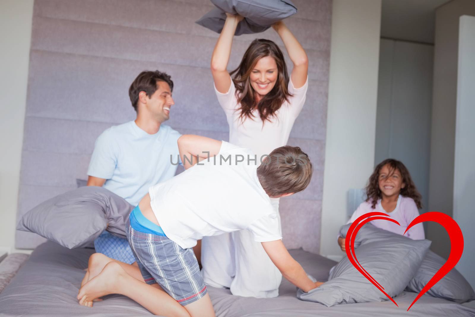 Family having a pillow fight on the bed against heart