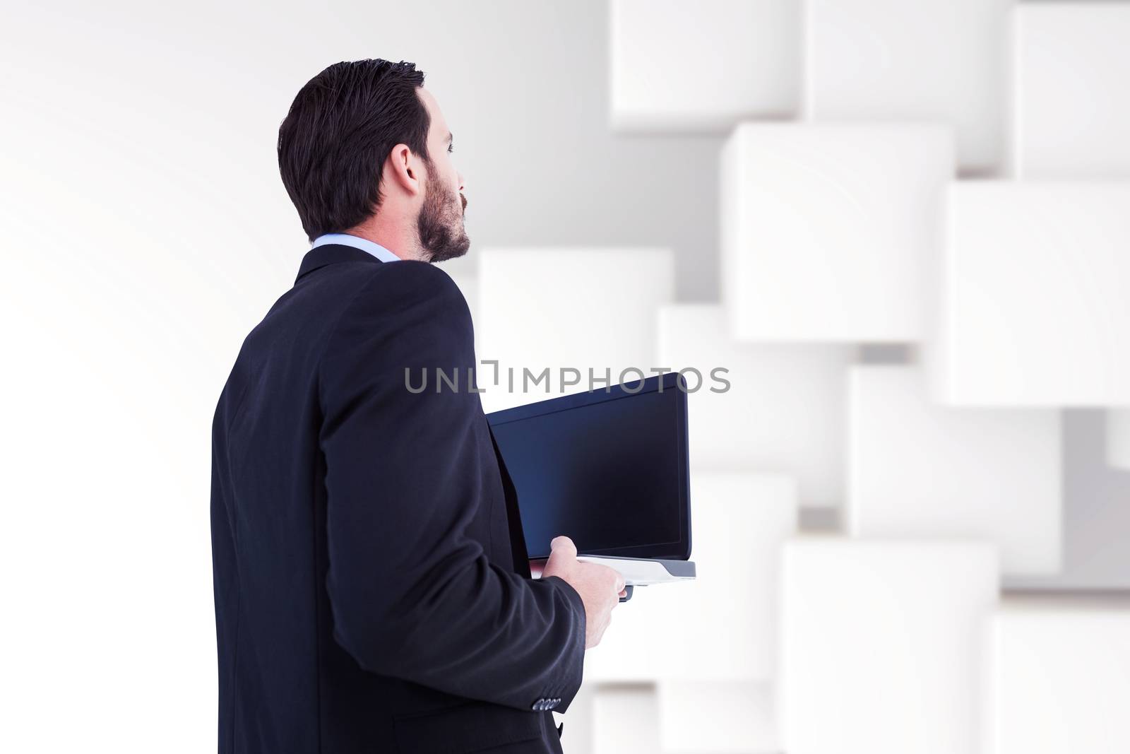 Businessman in suit holding laptop against abstract white design