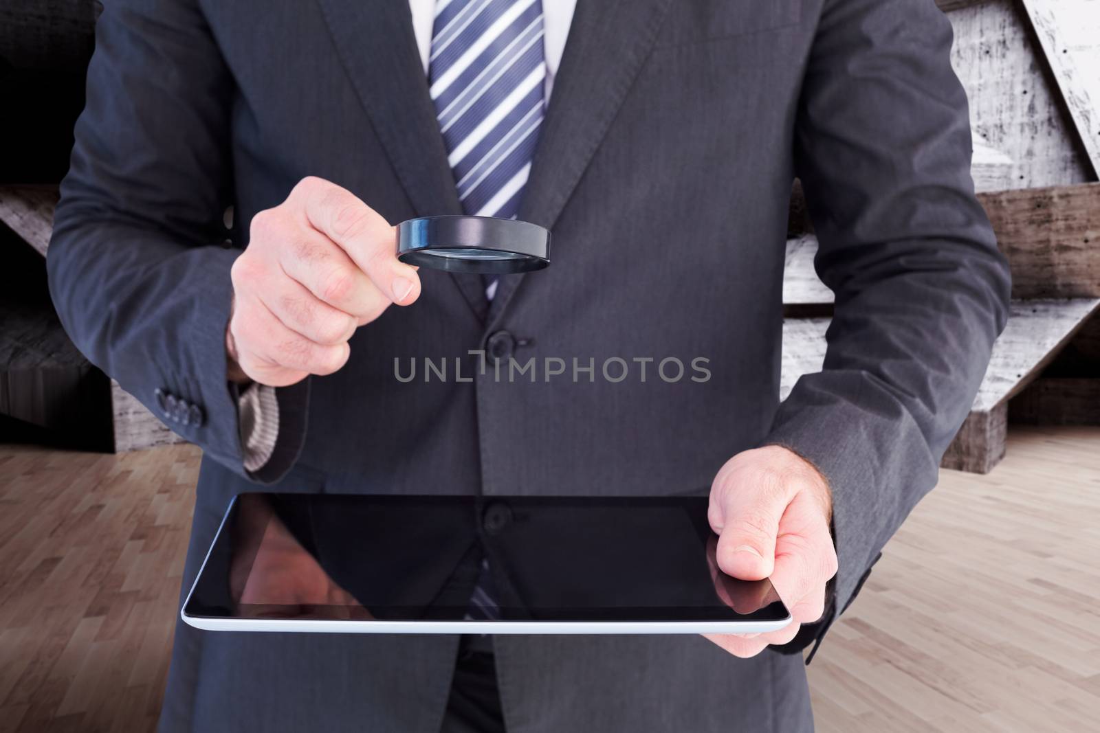 Composite image of businessman looking at tablet with magnifying glass by Wavebreakmedia