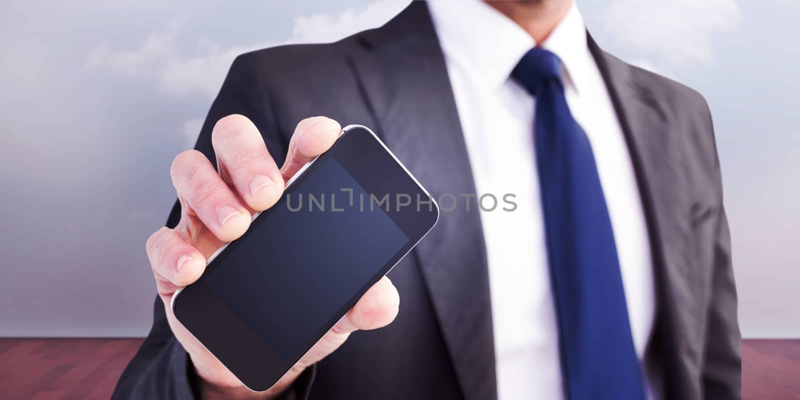 Businessman showing his smartphone screen against clouds in a room