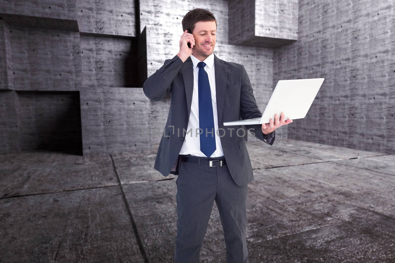 Businessman talking on phone holding laptop against abstract room