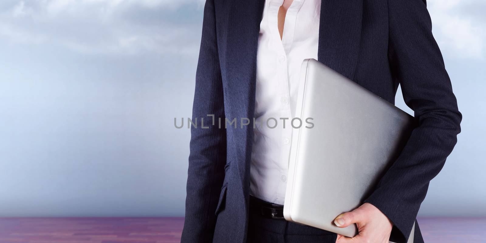 Businesswoman holding laptop against clouds in a room