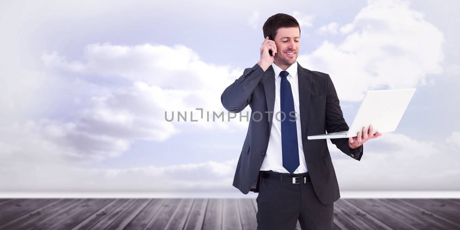 Businessman talking on phone holding laptop against clouds in a room