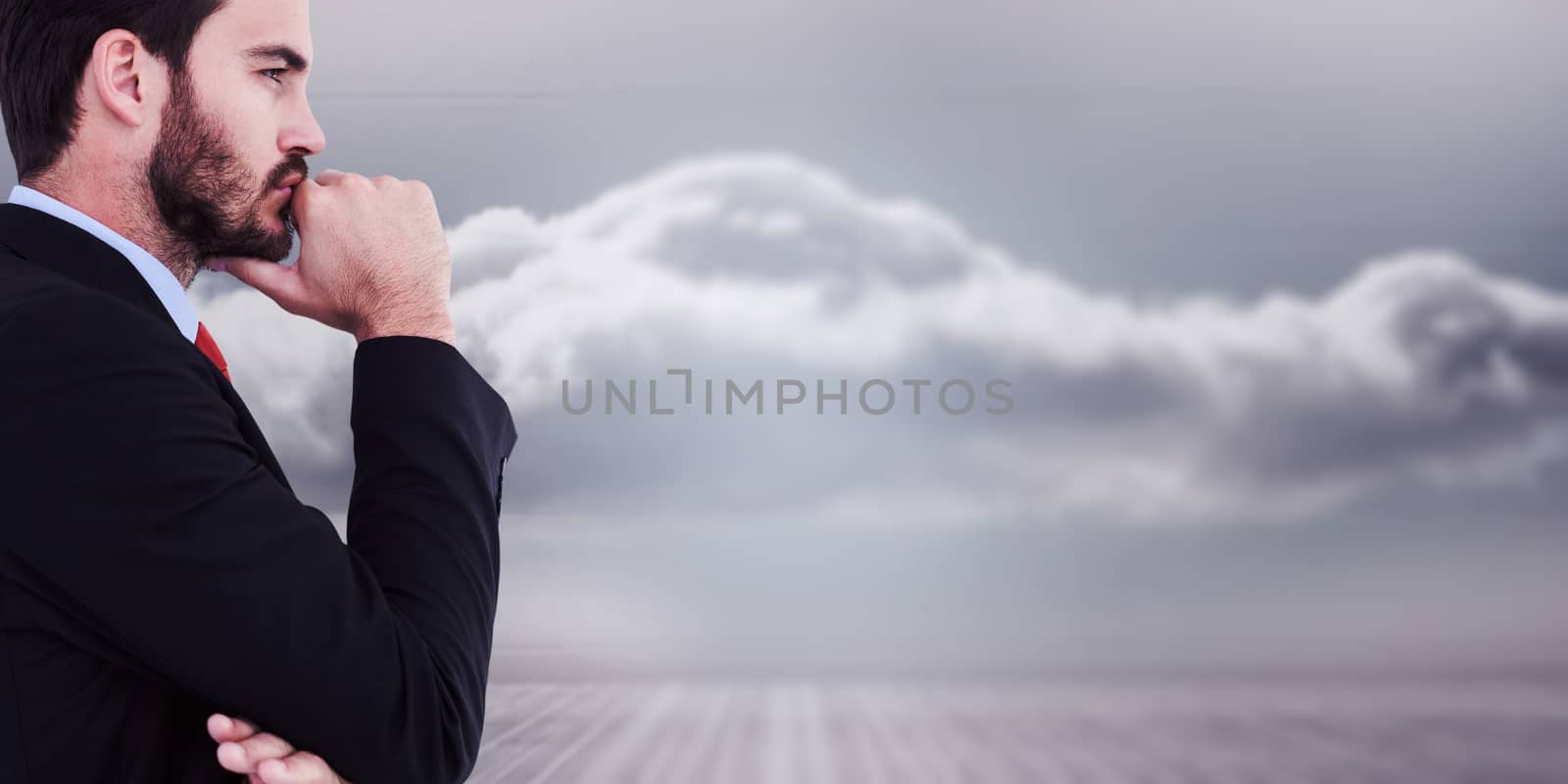 Thinking businessman standing with hand on chin against clouds in a room