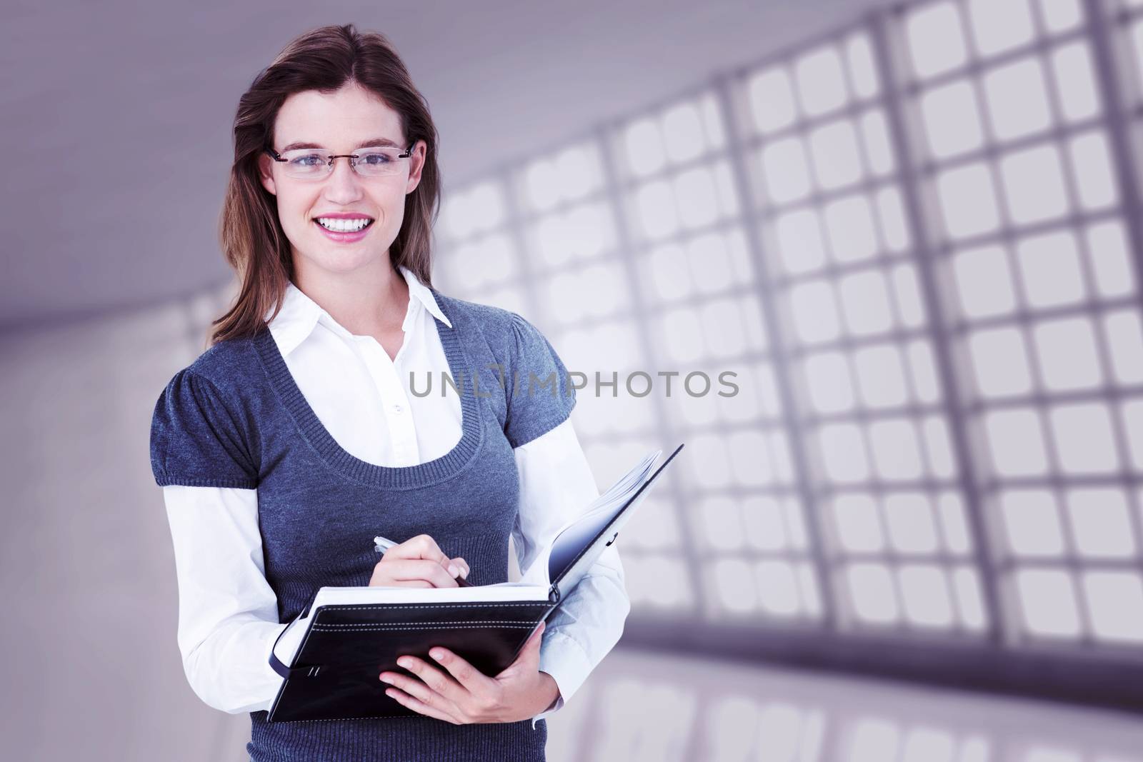 Happy woman writing in diary  against abstract room