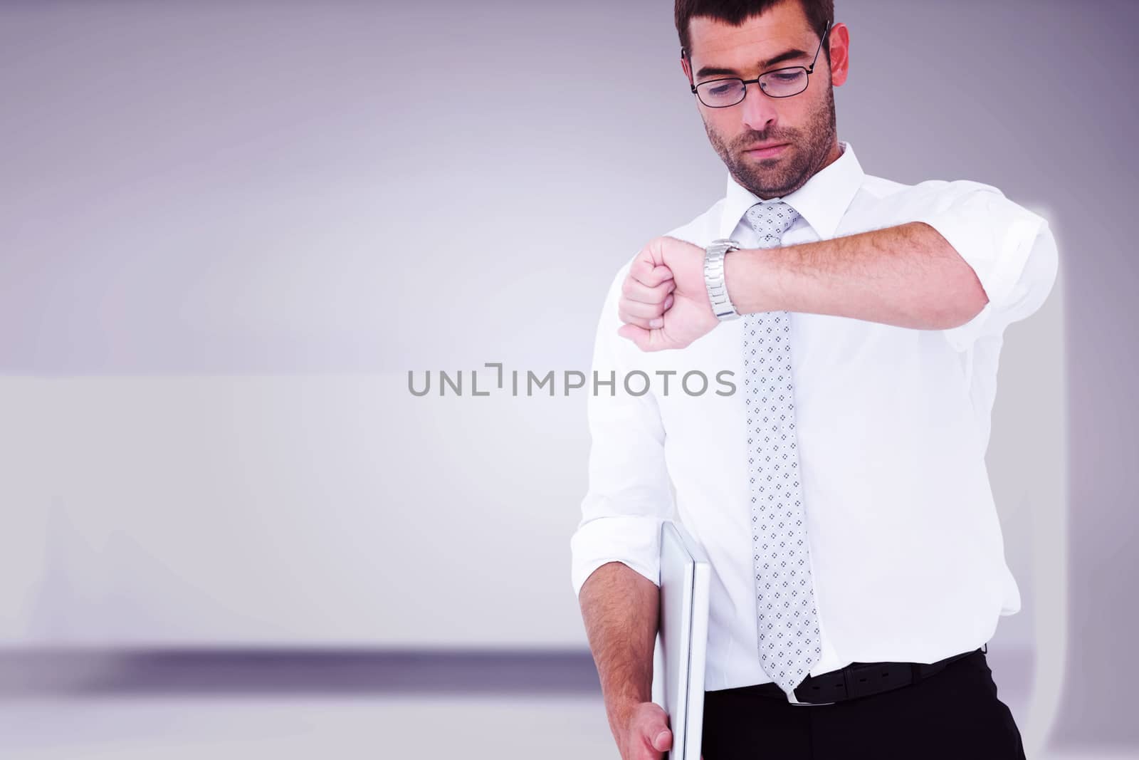 Serious businessman holding laptop checking time against abstract room
