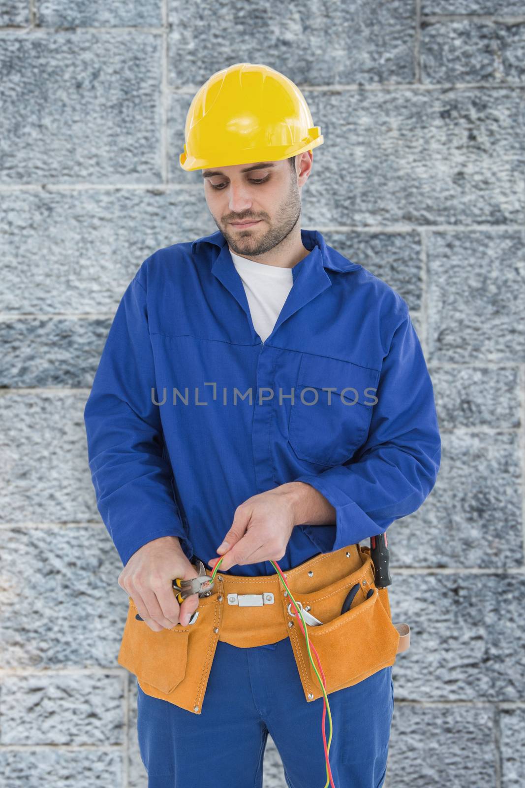 Male electrician cutting wires against grey