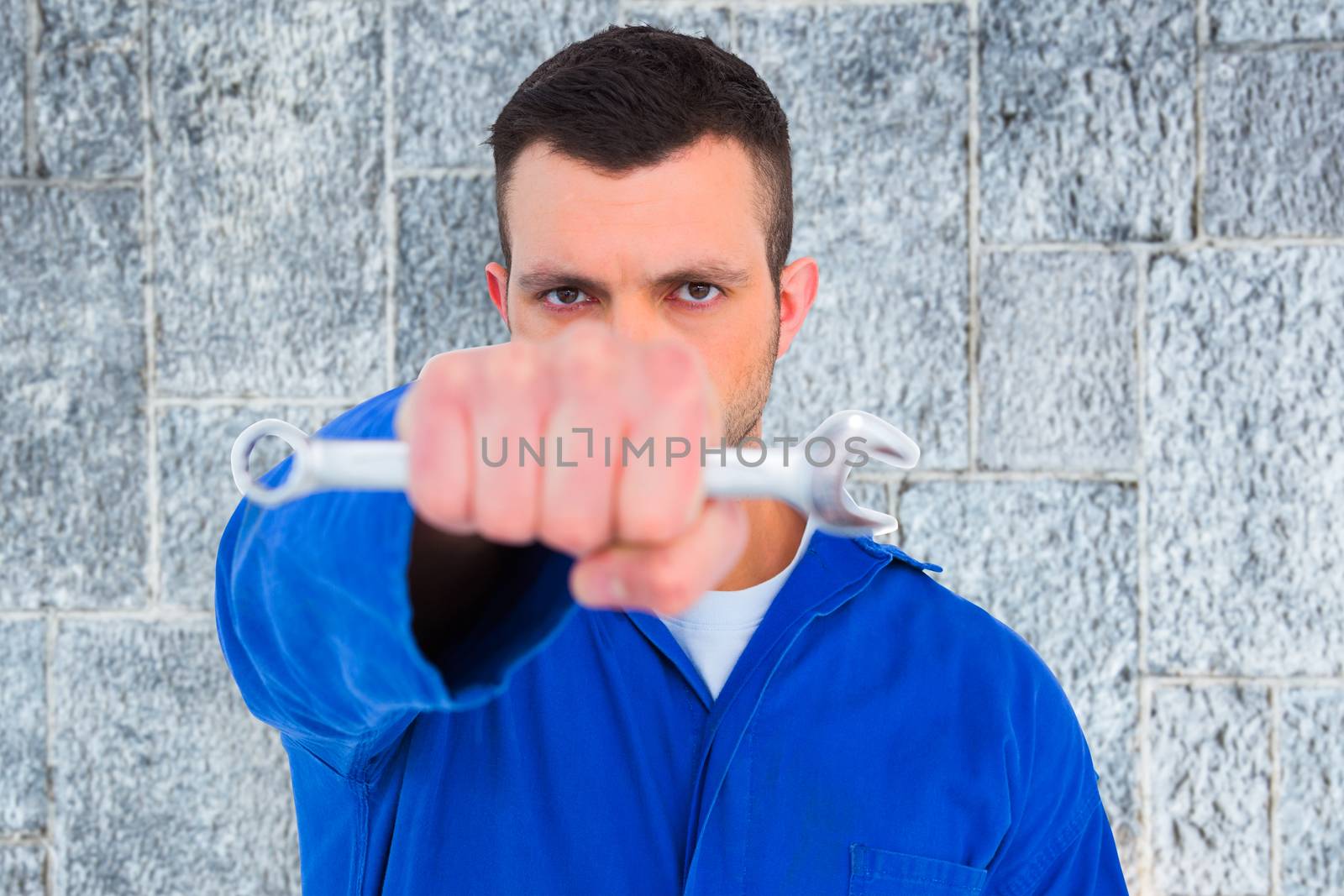 Composite image of confident male mechanic holding spanner by Wavebreakmedia