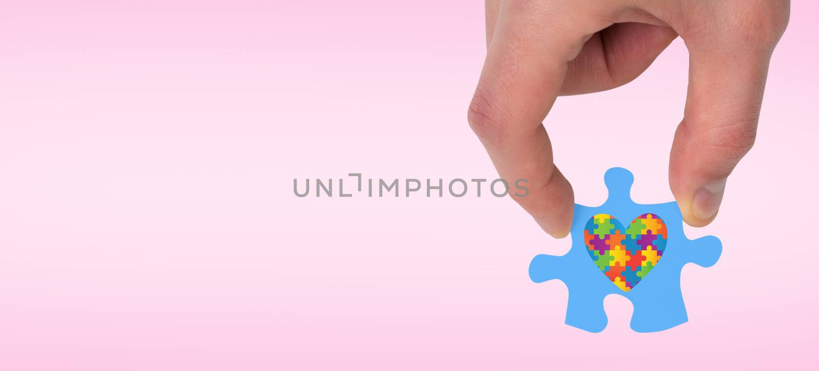 Hand holding jigsaw piece against pink