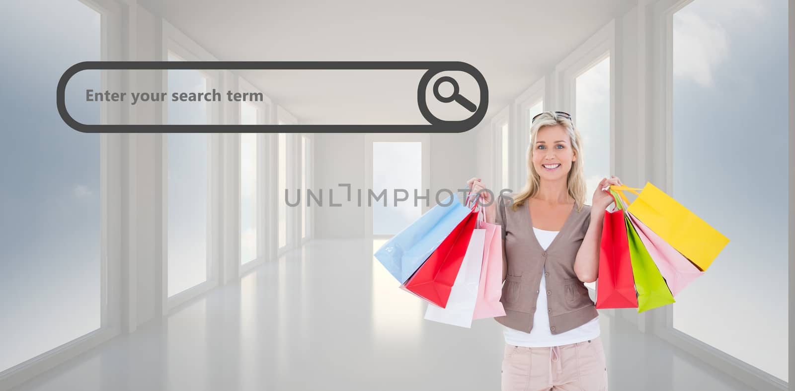 Happy blonde holding shopping bags against bright white hall with windows