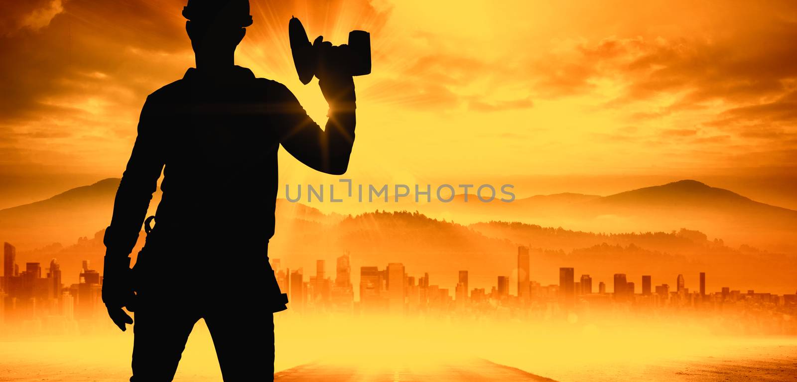Handyman wearing tool belt while holding power drill against sun shining over road and city