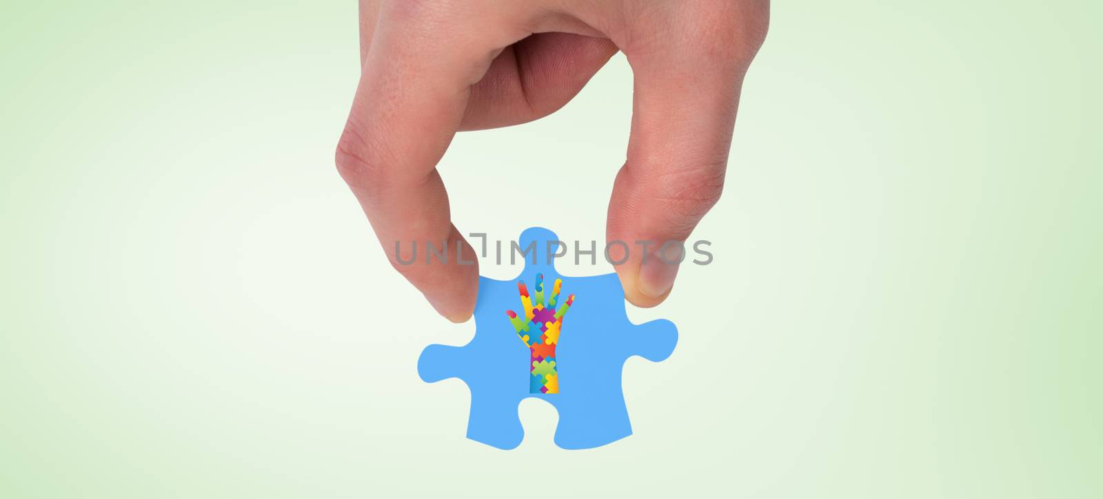 Hand holding jigsaw piece against green vignette