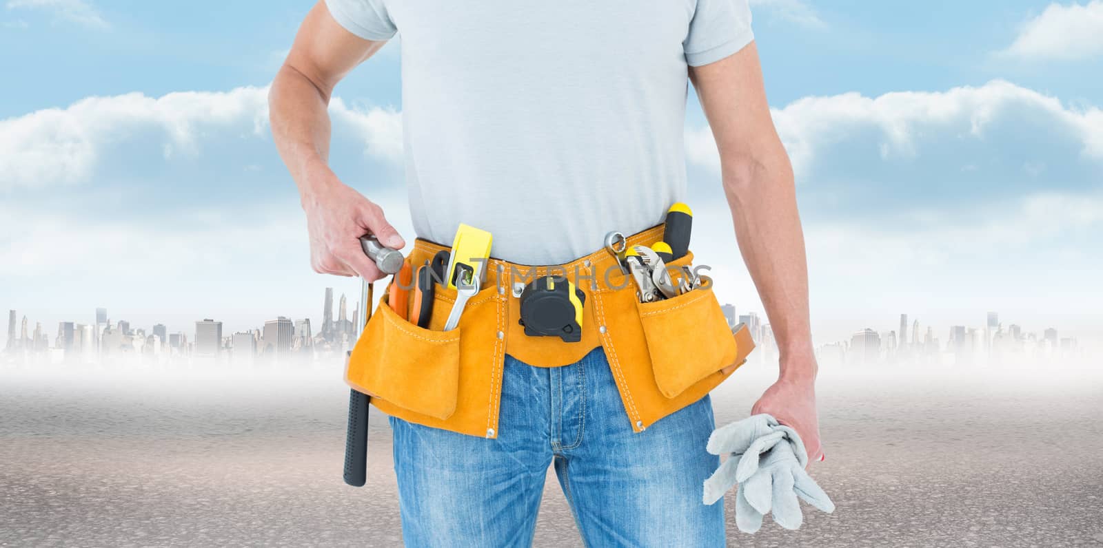 Technician holding gloves and hammer against city on the horizon