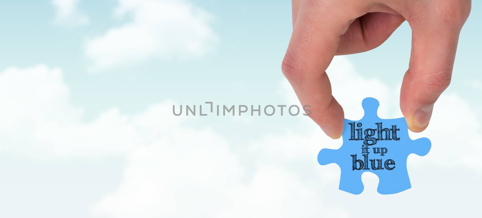 Hand holding jigsaw piece against blue sky