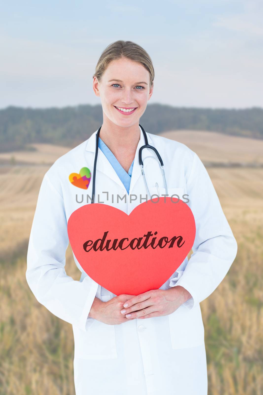 The word education and doctor holding red heart card  against rural fields against trees and sky