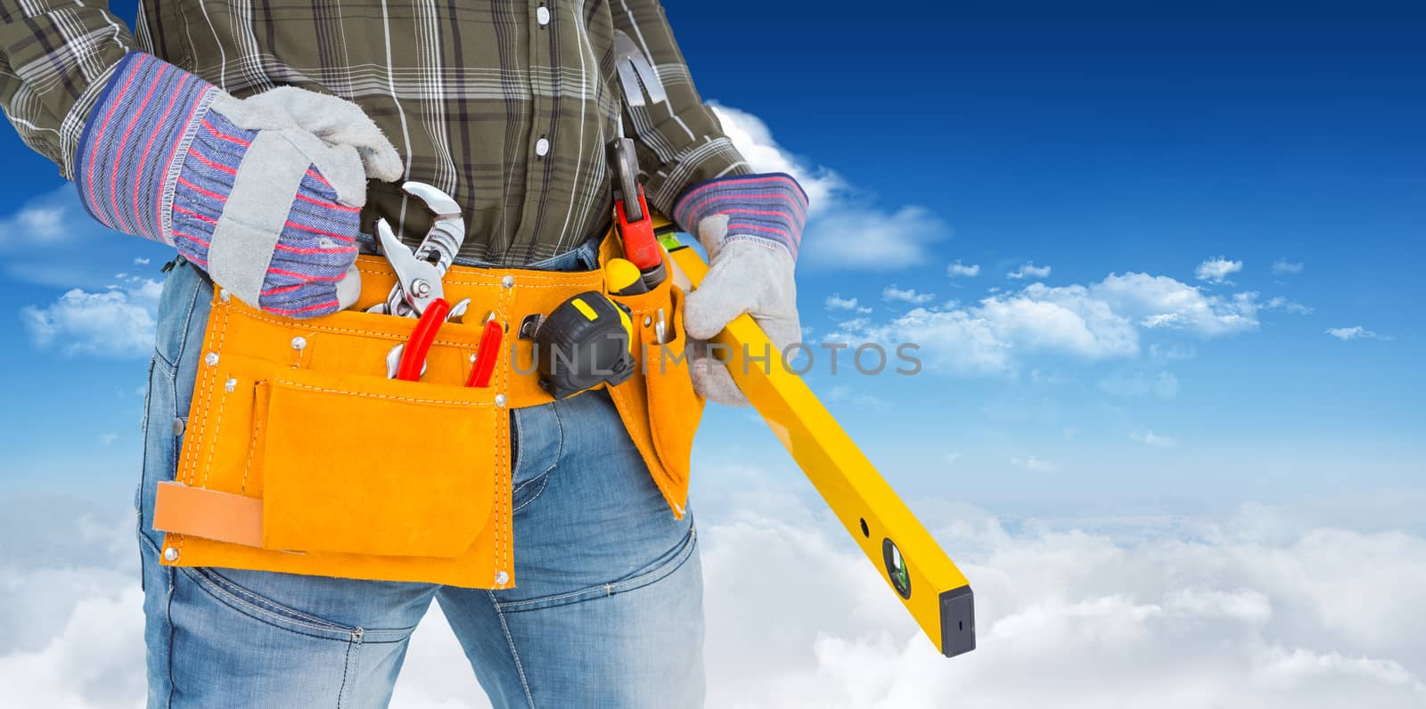 Handyman holding spirit level against bright blue sky with clouds