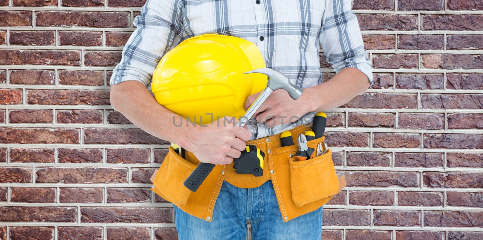 Technician holding hammer and hard hat against red brick wall