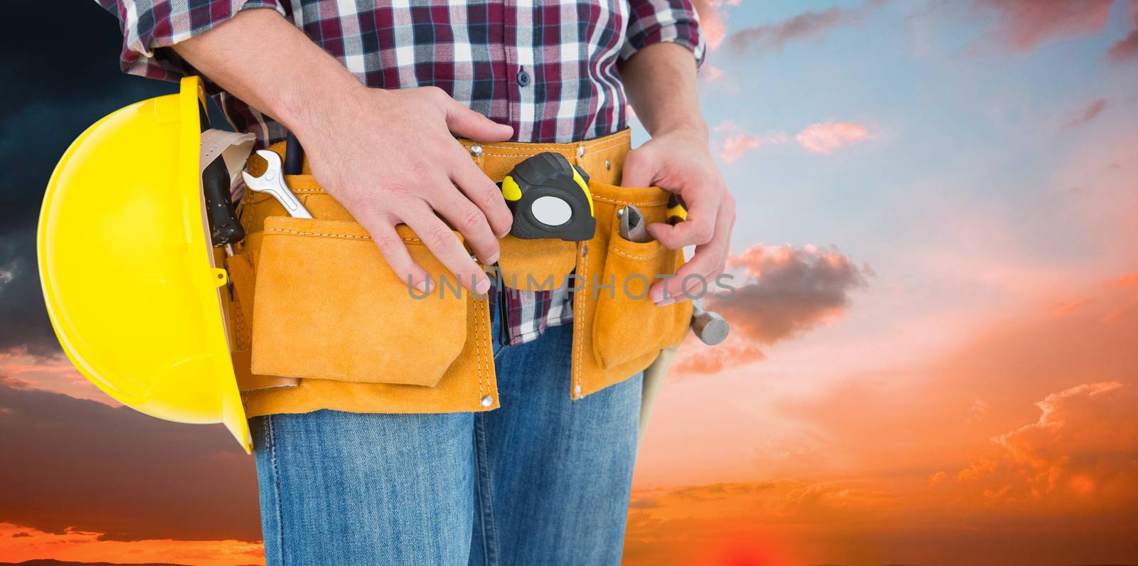 Handyman with tool belt and handyman against orange and blue sky with clouds