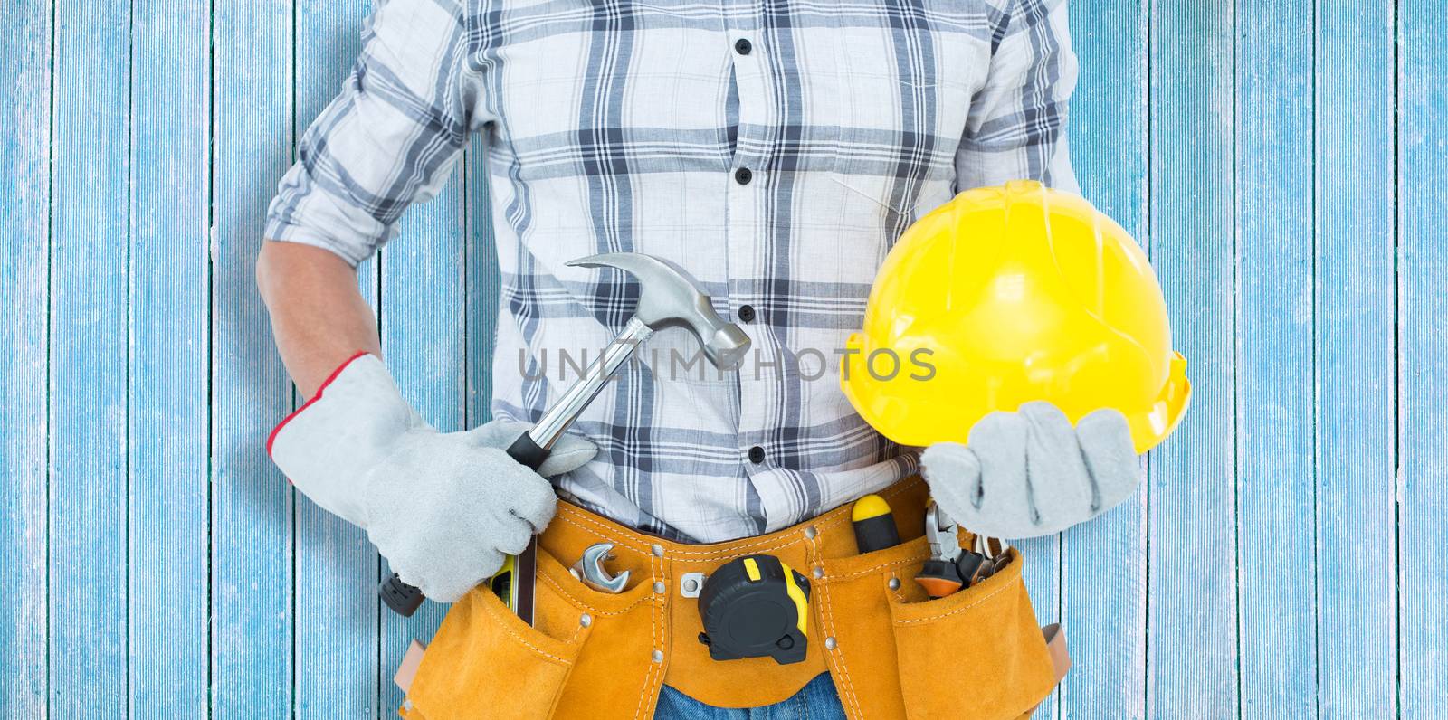 Handyman holding hammer and hard hat against wooden planks