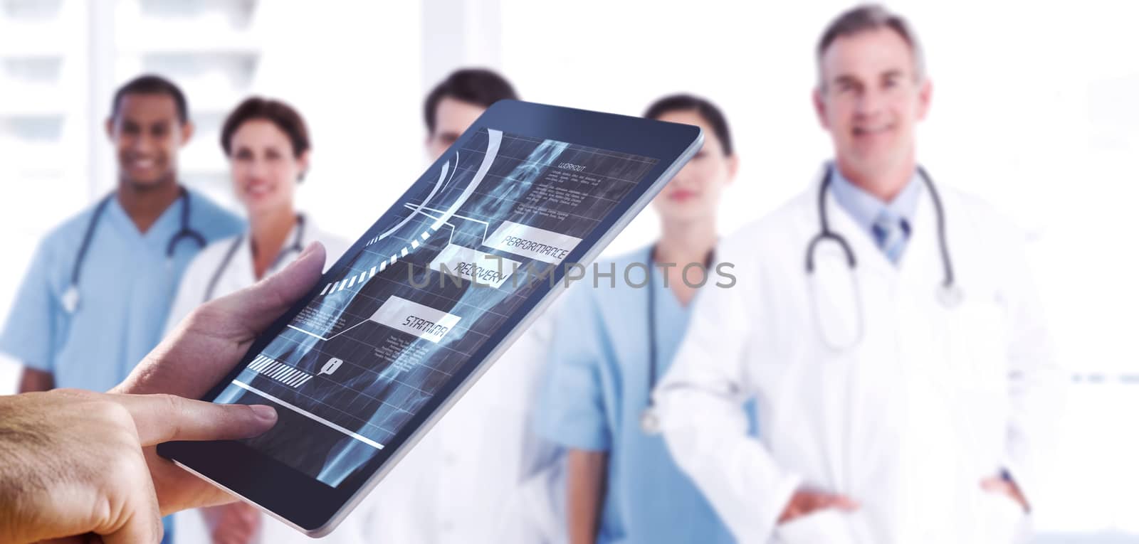 Man using tablet pc against portrait of doctors in a row at hospital