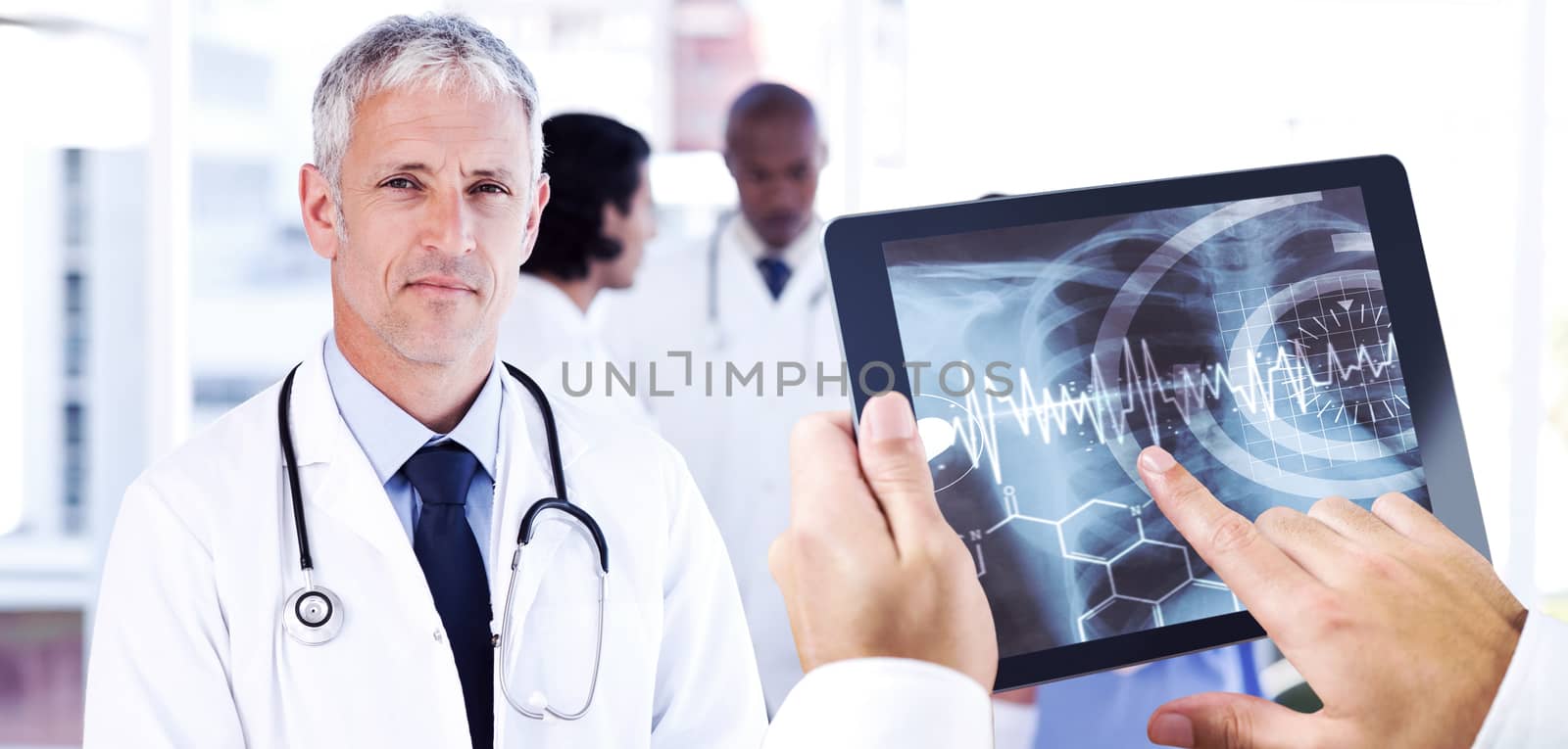 Man using tablet pc against mature doctor pointing at something on his clipboard