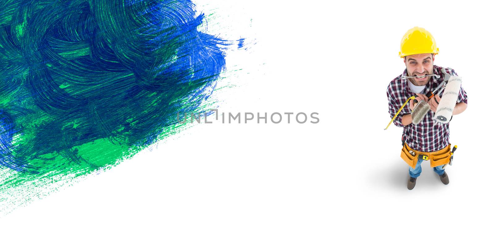 Frustrated handyman holding various tools against blue and green paint