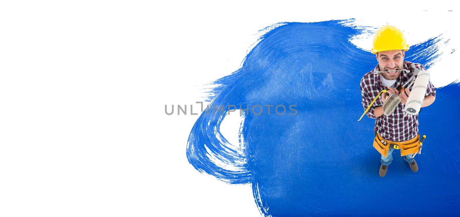 Frustrated handyman holding various tools against blue paint