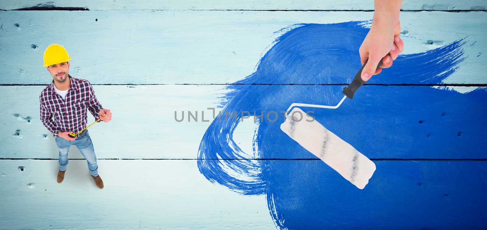 Handyman holding paint roller  against painted blue wooden planks