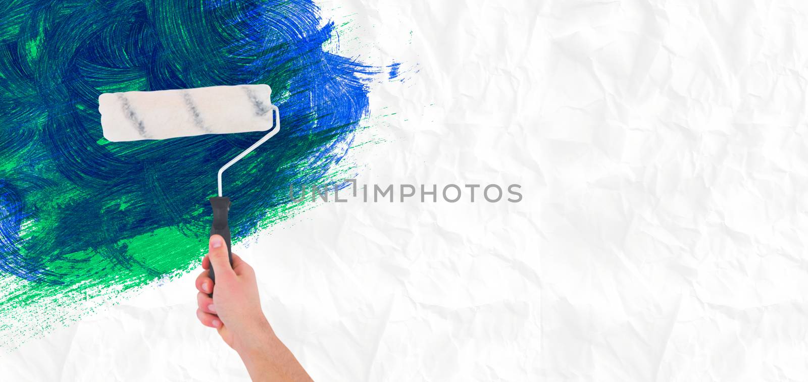 Handyman holding paint roller  against crumpled white page 