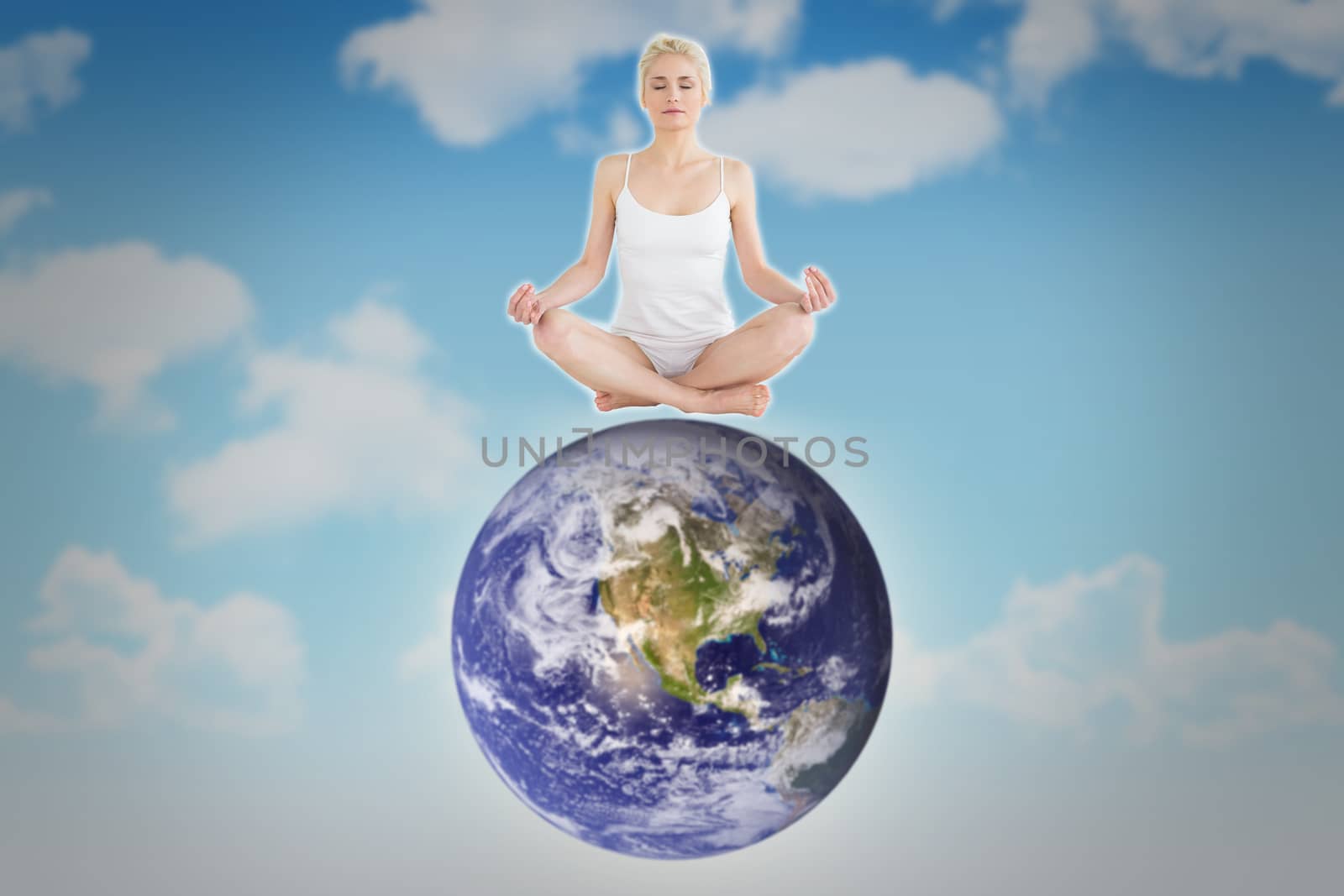 Toned young woman sitting in lotus pose with eyes closed against blue sky