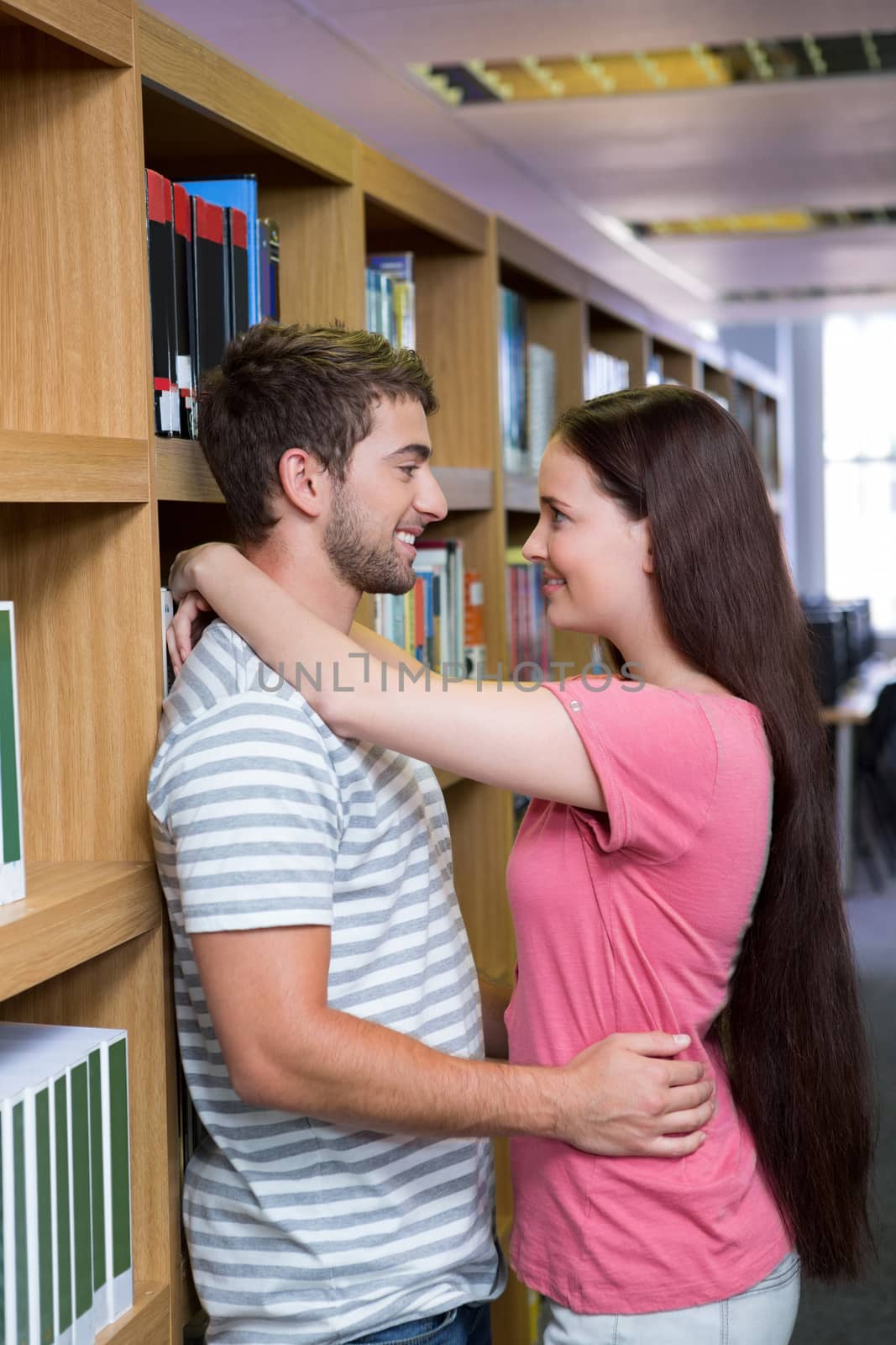 Cute couple embracing each other in the library by Wavebreakmedia