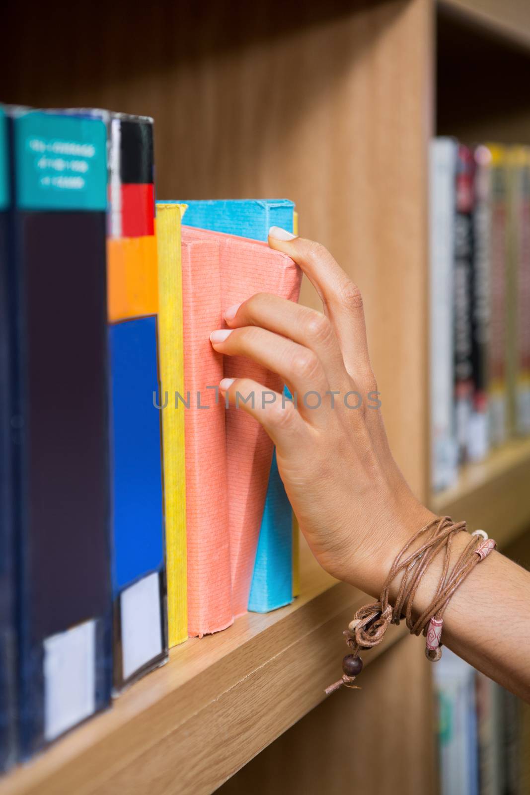 Student picking a book from shelf in library at the university