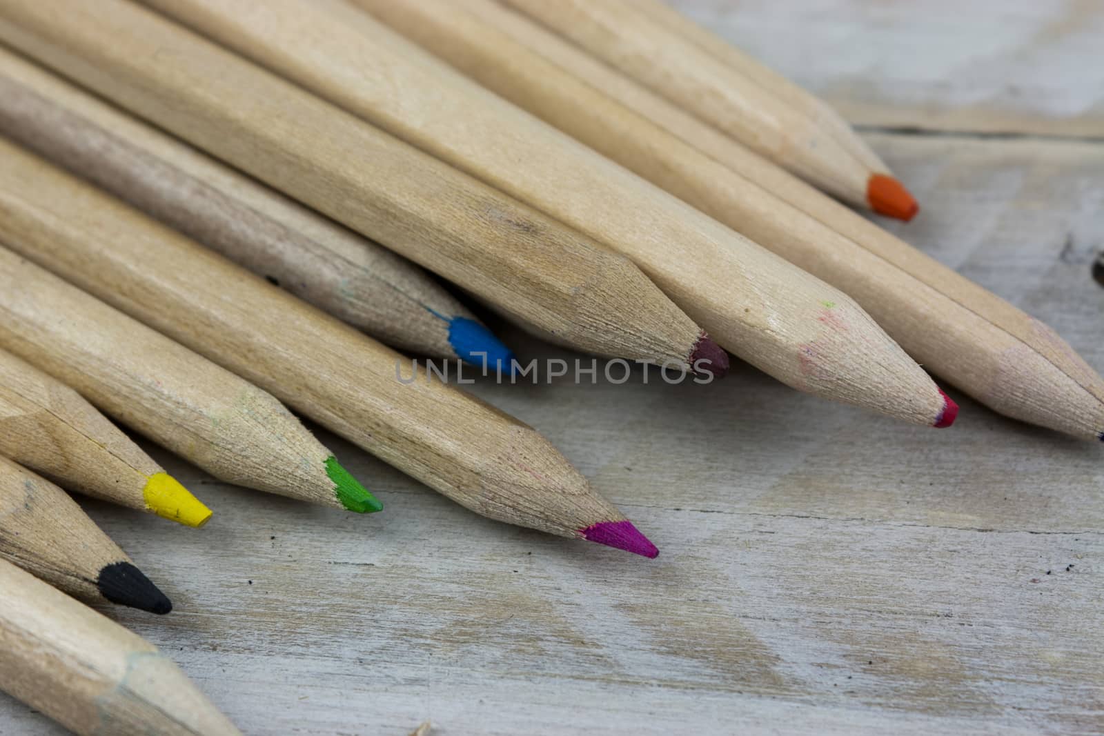 Close f of coloured pencils against a wooden background