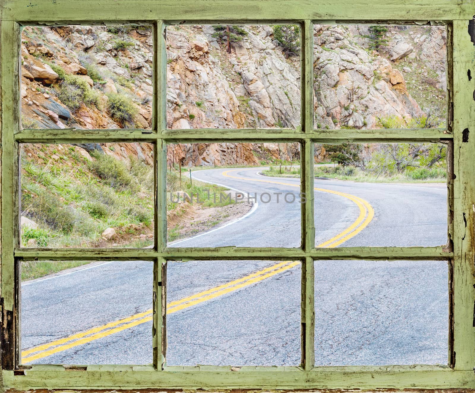 travel concept - a view of windy mountain road  through vintage, grunge, sash window with dirty glass