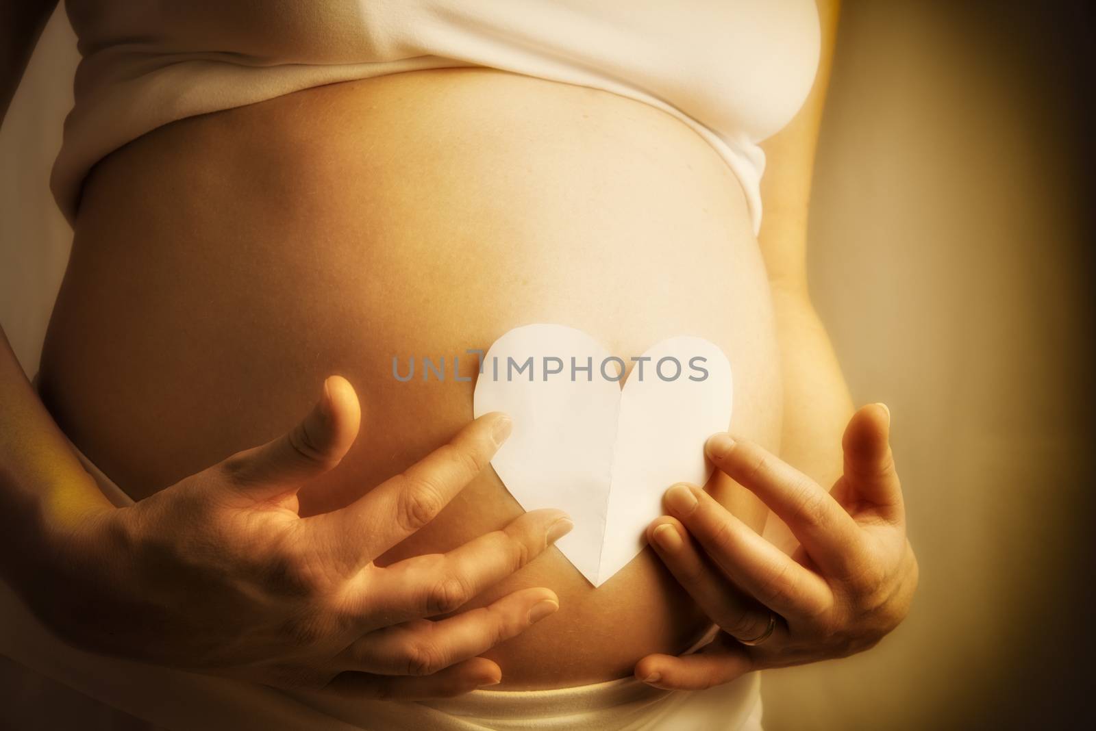 Pregnant woman with paper heart on her baby bump