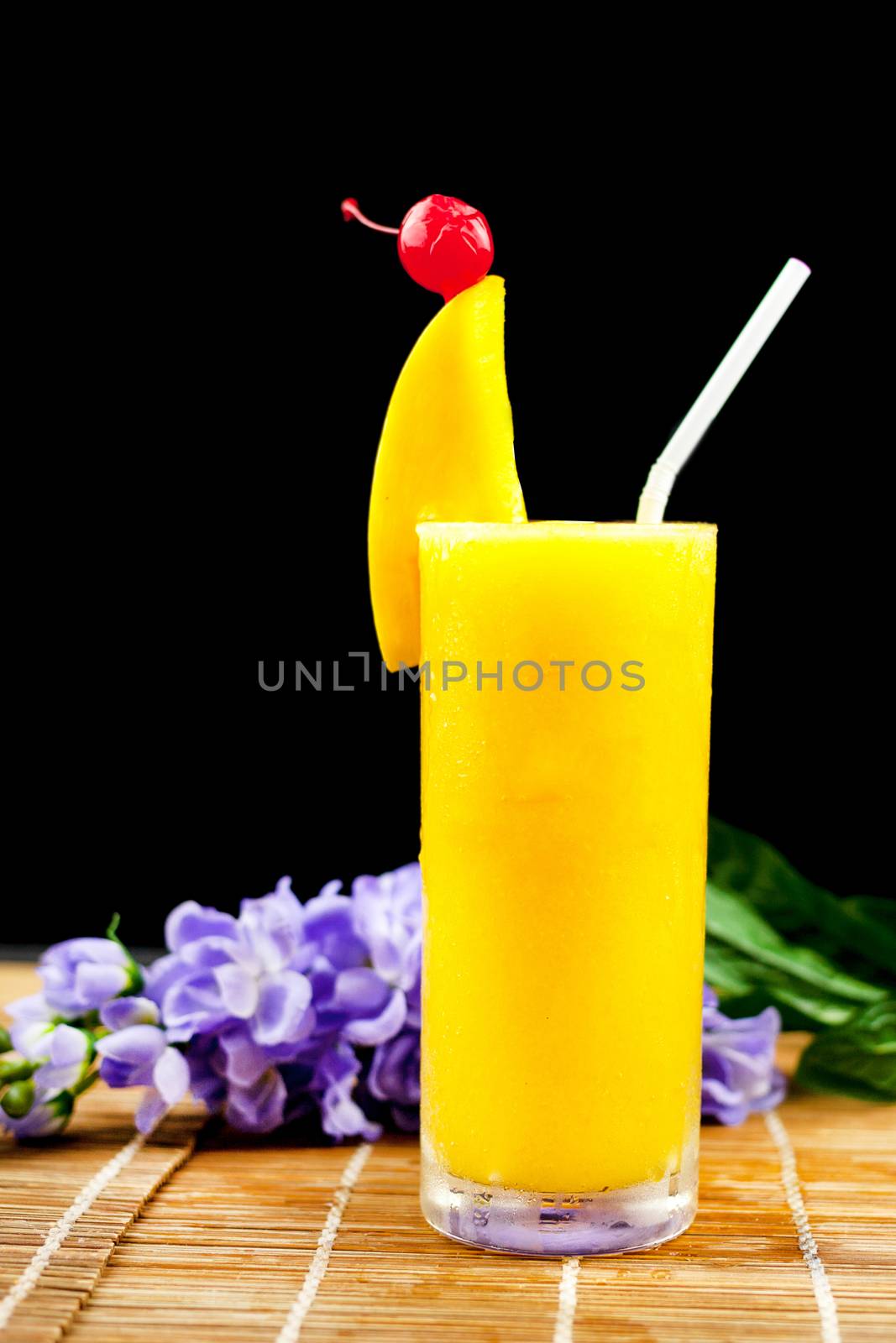 Mango juice and fruit on glass near flower isolation black backg by nopparats