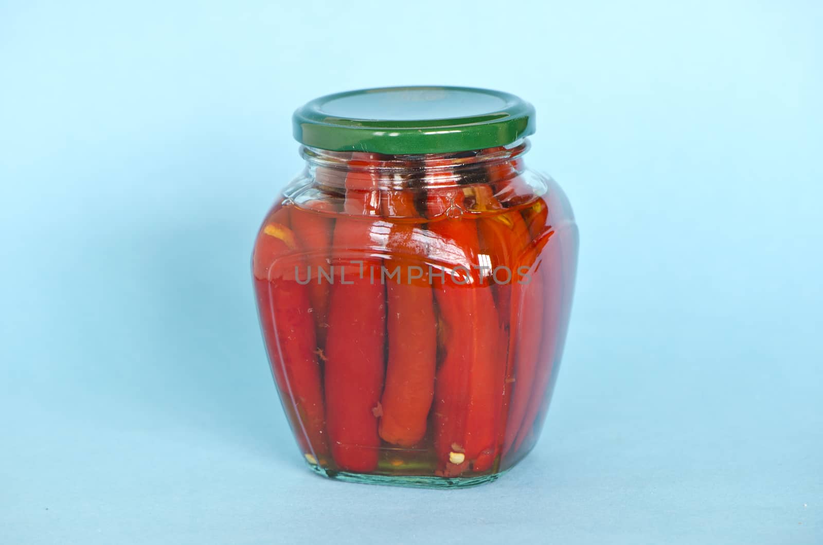 ecological red hot chilli pepper paprika preserved canned in glass pot on blue background