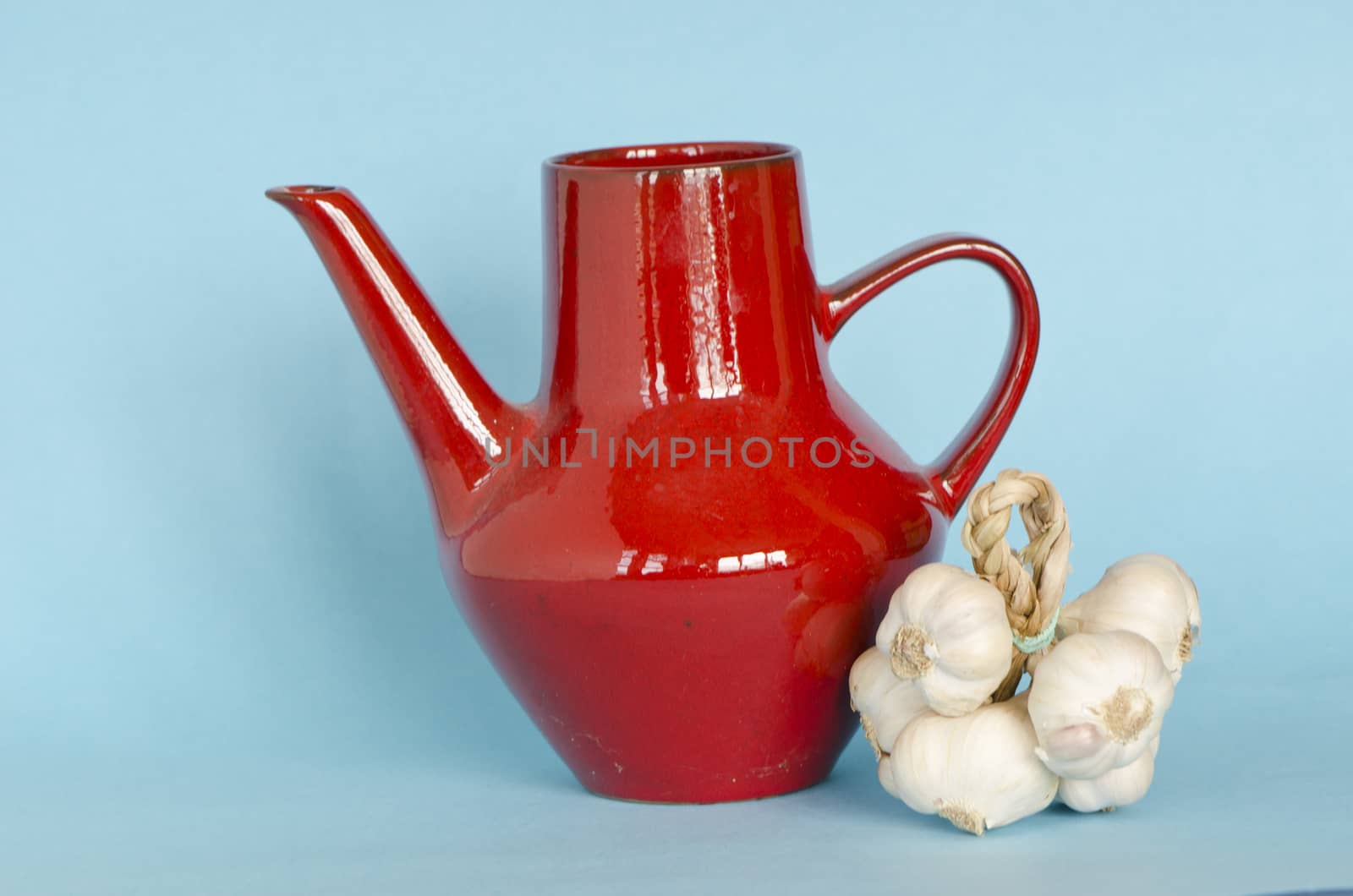 red ceramic jar pitcher and healthy garlic bulb bunch on azure background