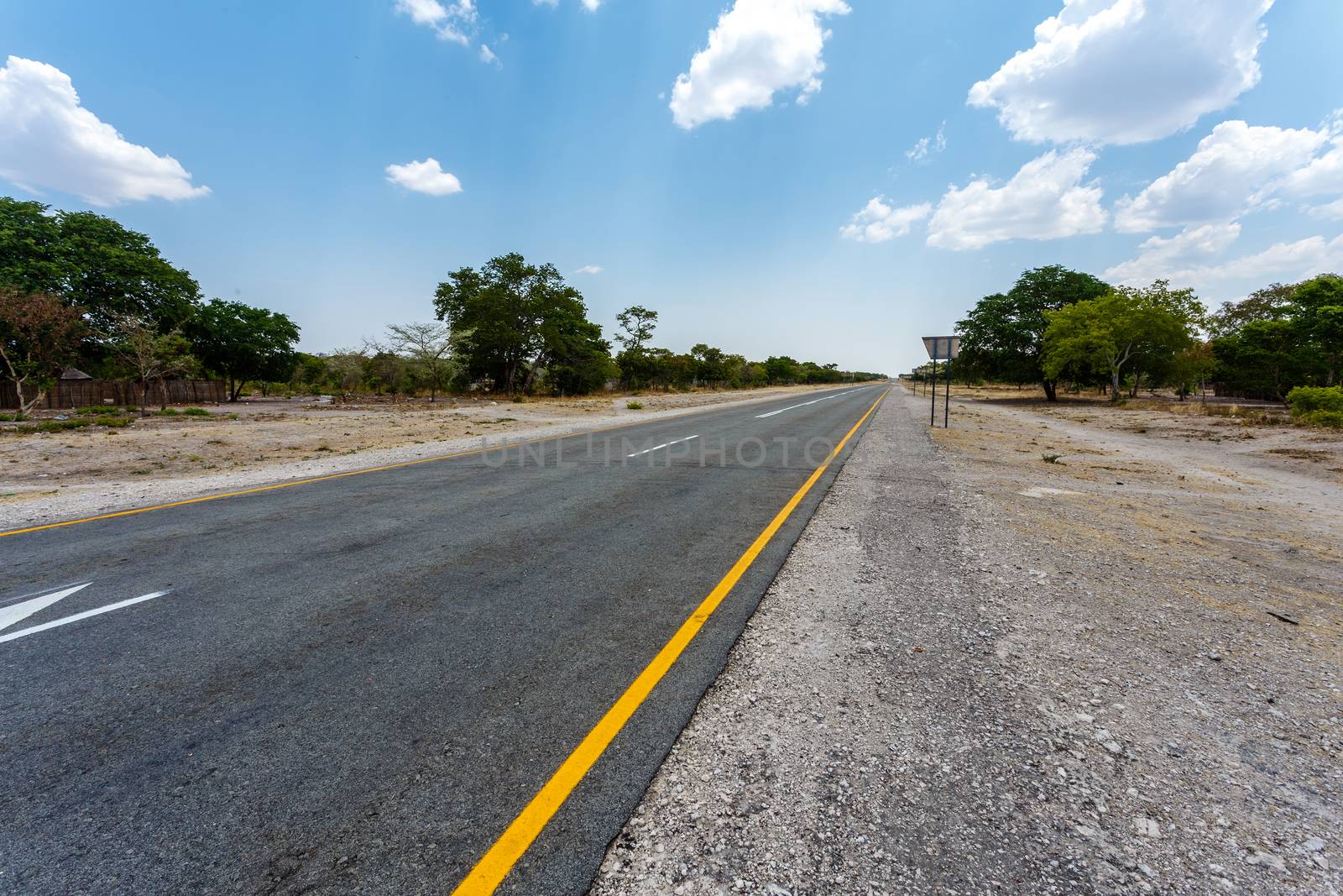 Endless road in Namibia, Caprivi Game Park, with blue sky